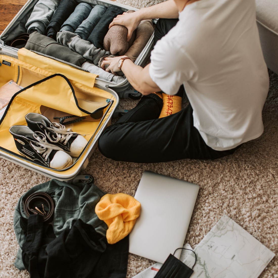 guy packing shoes, clothese, and essentials for a trip